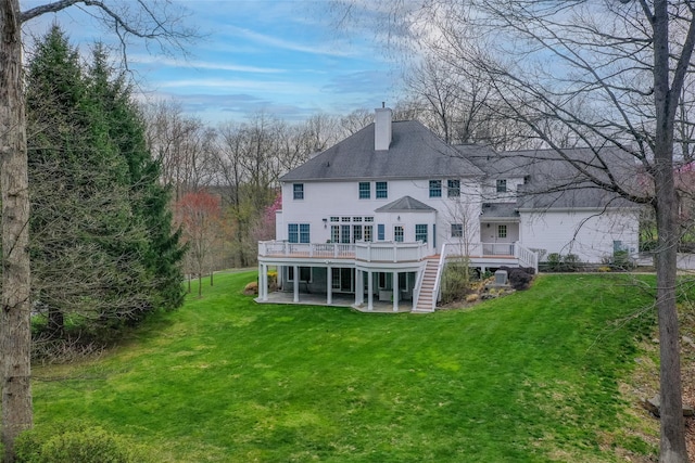 back of house featuring a patio area, a chimney, a lawn, a deck, and stairs