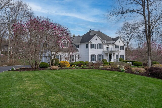 view of front of home featuring a front yard, a balcony, and aphalt driveway