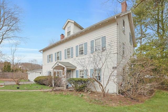 colonial inspired home featuring a chimney and a front lawn
