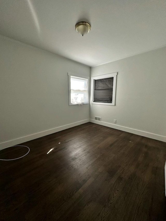 spare room with visible vents, baseboards, and dark wood finished floors