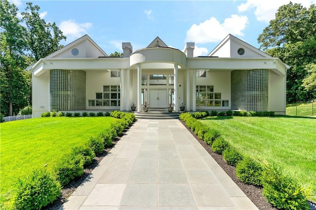 view of front of property featuring stucco siding, a front lawn, and a chimney