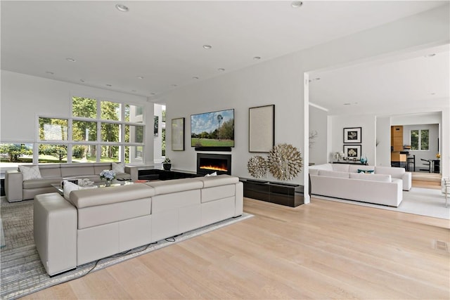 living area with wood finished floors, recessed lighting, and a lit fireplace