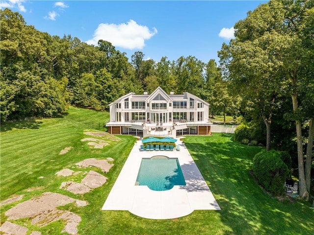 rear view of property featuring a patio area, an outdoor pool, a deck, a yard, and a sunroom