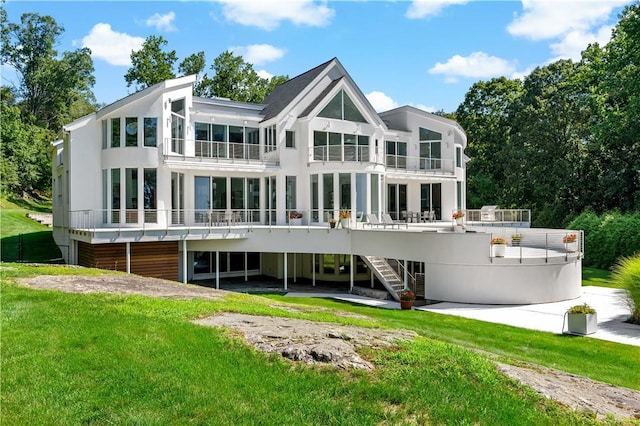 back of property with a yard, stairway, and a balcony