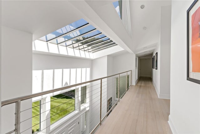 hallway featuring light wood-style floors, a healthy amount of sunlight, and baseboards