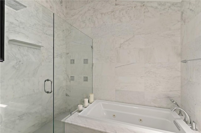 bathroom with a whirlpool tub, a marble finish shower, and tile walls