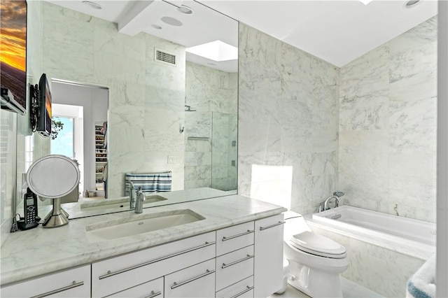 full bathroom featuring tiled bath, vanity, tile walls, toilet, and visible vents