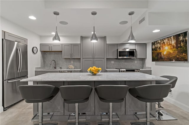 kitchen with gray cabinetry, a sink, backsplash, and appliances with stainless steel finishes