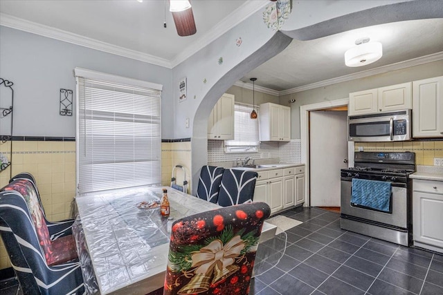 232 Courthouse Rd, Franklin Square, NY 11010 - kitchen featuring tile walls, dark tile patterned floors, stainless steel appliances, arched walkways, and white cabinets