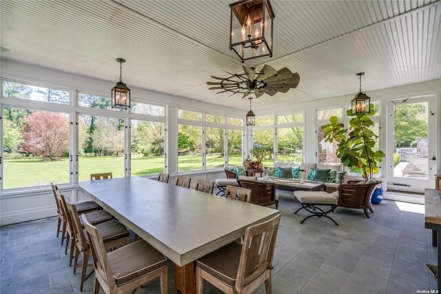 sunroom featuring ceiling fan with notable chandelier, outdoor lounge area, and a healthy amount of sunlight