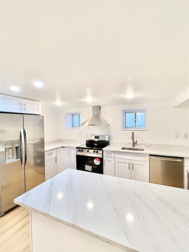 kitchen with light stone countertops, wall chimney exhaust hood, stainless steel appliances, and a sink
