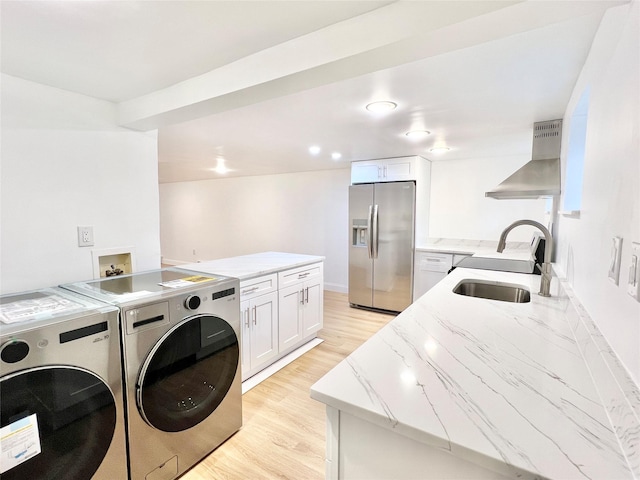 laundry area featuring washing machine and dryer, light wood-style floors, a sink, and laundry area