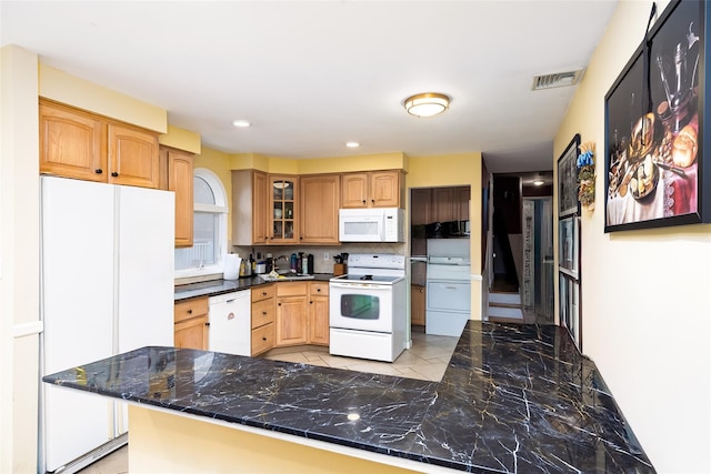 kitchen featuring dark countertops, tasteful backsplash, white appliances, glass insert cabinets, and visible vents