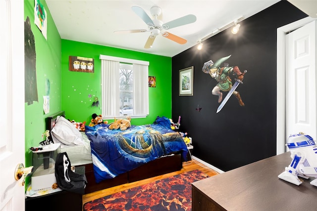 bedroom featuring track lighting, wood finished floors, and a ceiling fan