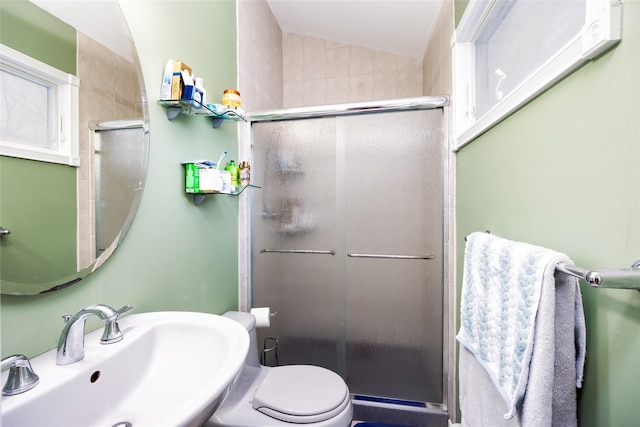 bathroom with toilet, lofted ceiling, a sink, and a stall shower