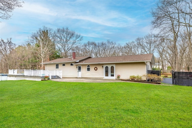 rear view of house featuring a chimney, french doors, fence, a yard, and a wooden deck