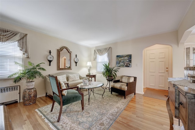 living area with radiator, light wood-style floors, and baseboards
