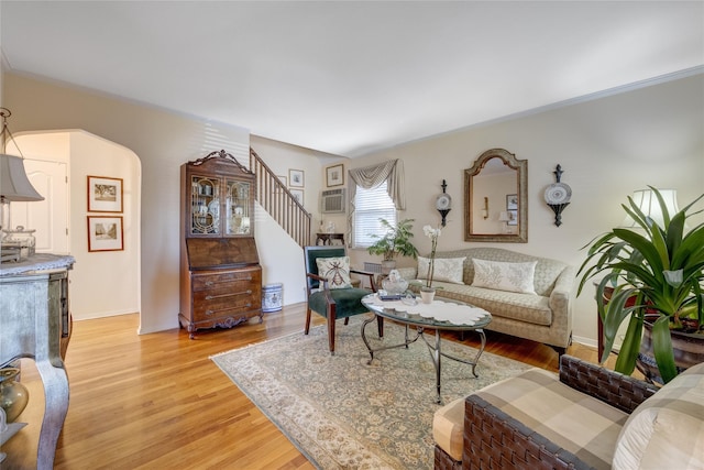 living area featuring stairway, light wood finished floors, crown molding, and baseboards