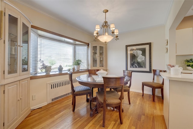 dining area with radiator, light wood-style flooring, a chandelier, crown molding, and baseboards