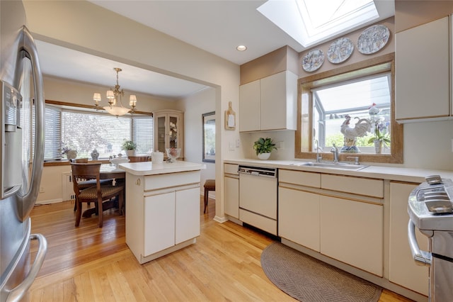 kitchen with white dishwasher, stainless steel fridge, a skylight, a sink, and light wood-type flooring
