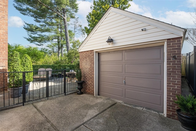 detached garage with concrete driveway and fence