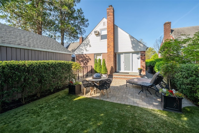 rear view of property with brick siding, a patio area, and a chimney