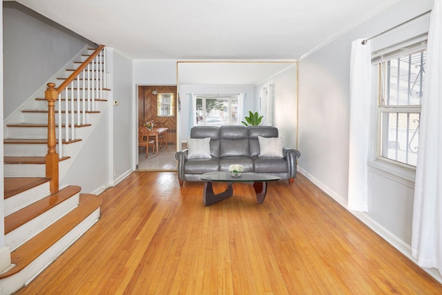 sitting room featuring stairway, baseboards, crown molding, and light wood finished floors