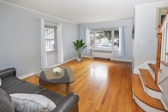living room with baseboards, ornamental molding, stairway, light wood-style flooring, and radiator