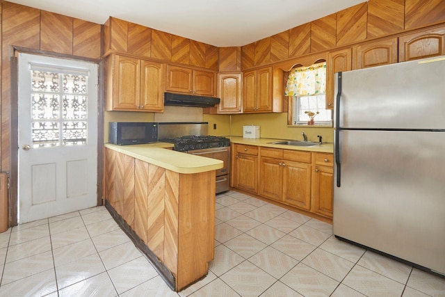 kitchen featuring a peninsula, light countertops, under cabinet range hood, appliances with stainless steel finishes, and a sink