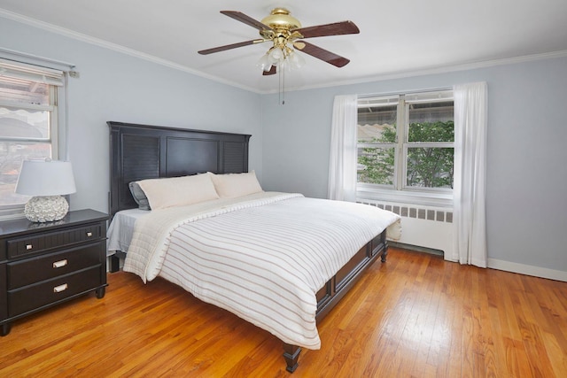 bedroom featuring light wood-type flooring, multiple windows, crown molding, and radiator