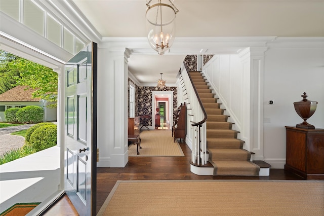 entrance foyer featuring a notable chandelier, baseboards, decorative columns, wood finished floors, and stairway