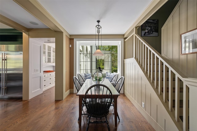 dining space featuring dark wood-style flooring, baseboards, and stairway