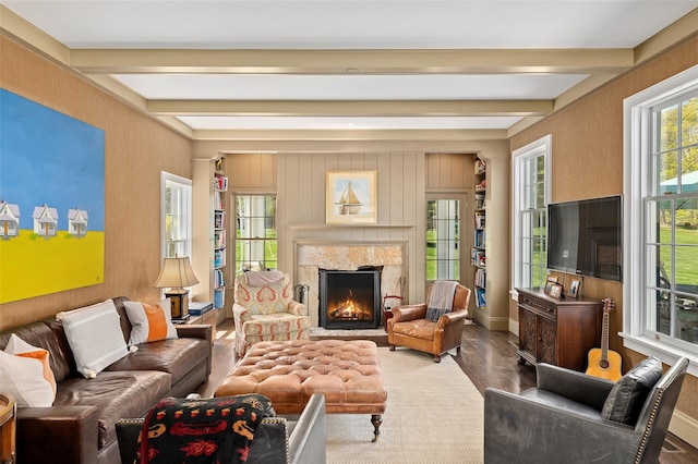 living area featuring baseboards, beam ceiling, wood finished floors, and a premium fireplace