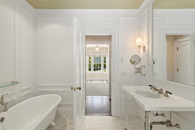 full bathroom with vanity, a freestanding tub, and a decorative wall
