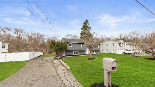 view of front facade with fence, a front lawn, aphalt driveway, and a residential view