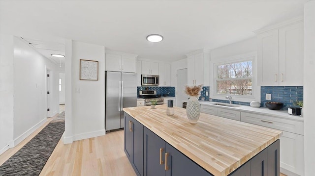 kitchen featuring white cabinets, butcher block counters, tasteful backsplash, and stainless steel appliances