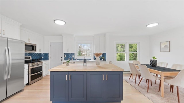 kitchen with white cabinets, light wood-style flooring, decorative backsplash, and stainless steel appliances