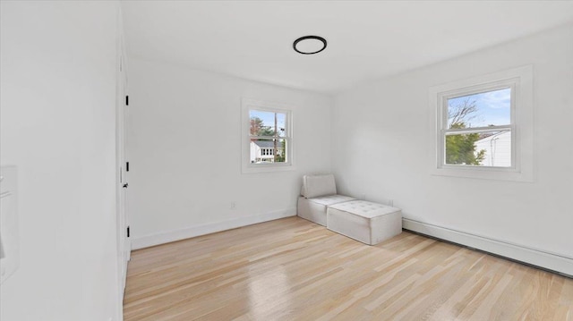 unfurnished room with a baseboard radiator, light wood-type flooring, and baseboards