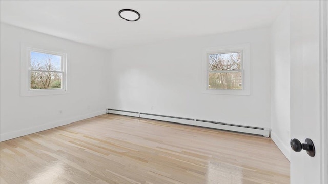 spare room with baseboards, baseboard heating, and wood finished floors