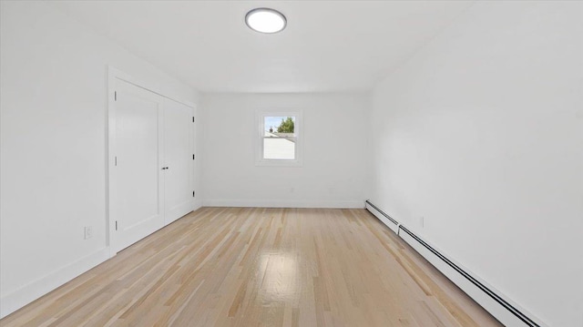 unfurnished bedroom with a baseboard radiator, light wood-style floors, and baseboards