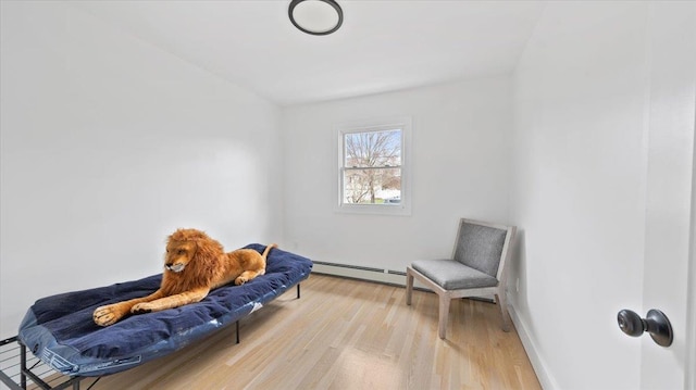 living area featuring a baseboard radiator, baseboards, and light wood finished floors