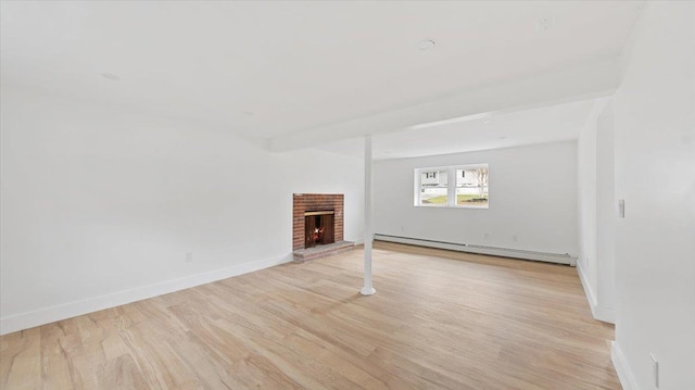 unfurnished living room featuring a baseboard heating unit, a brick fireplace, baseboards, and light wood-style floors