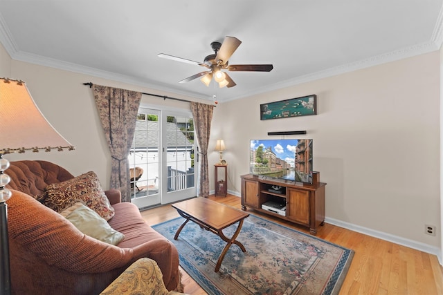 living area featuring light wood-style floors, baseboards, ornamental molding, and a ceiling fan