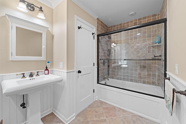 full bathroom featuring crown molding, enclosed tub / shower combo, wainscoting, and a sink