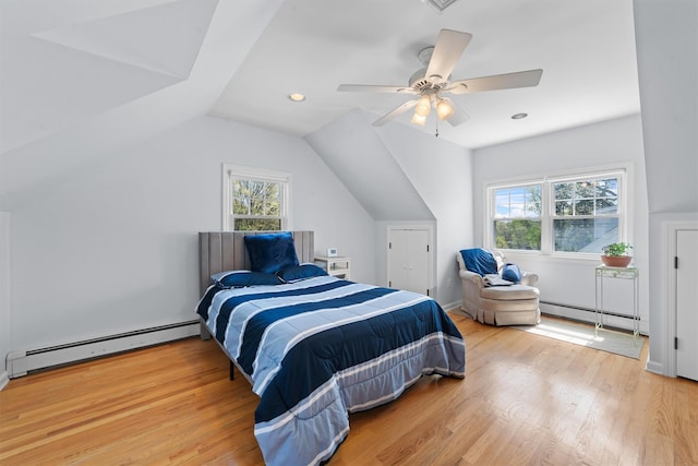 bedroom featuring a baseboard heating unit, multiple windows, and light wood finished floors