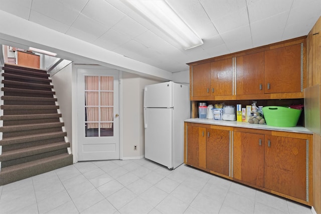kitchen with freestanding refrigerator, brown cabinets, and light countertops