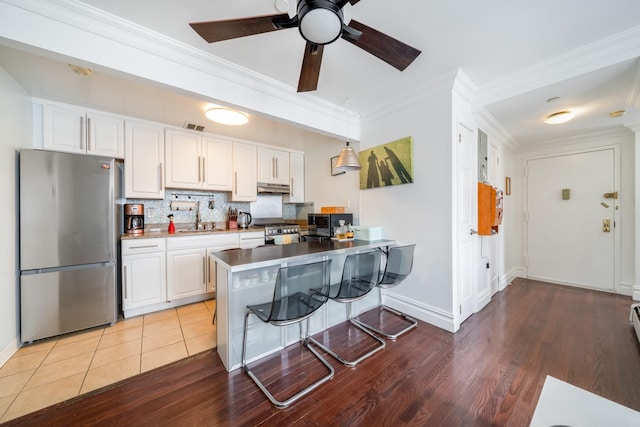 49-07 43rd Ave Unit 7F, Sunnyside, NY 11377 - kitchen featuring light wood-type flooring, stainless steel appliances, under cabinet range hood, and crown molding