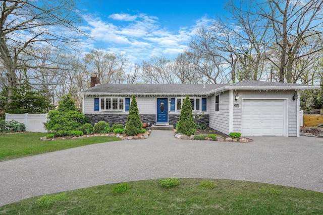 single story home featuring a chimney, aphalt driveway, stone siding, fence, and a garage