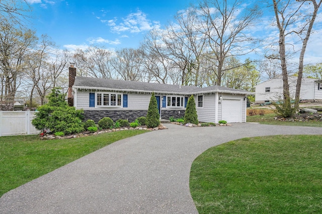 ranch-style house with driveway, a chimney, fence, an attached garage, and a front yard