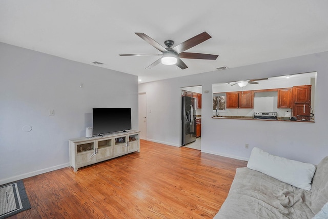 living area with baseboards, a ceiling fan, visible vents, and light wood-style flooring